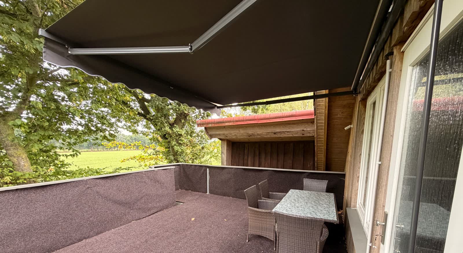 Überdachte Terrasse mit elektrischer Markise, Gartenmöbeln und Blick ins Grüne